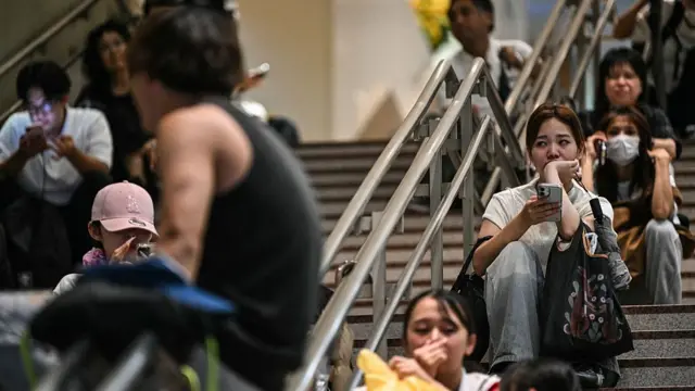 Stranded passengers sit on the floor at Chiba Metro Station