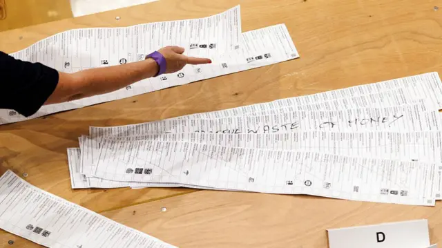 A person points at by-election papers