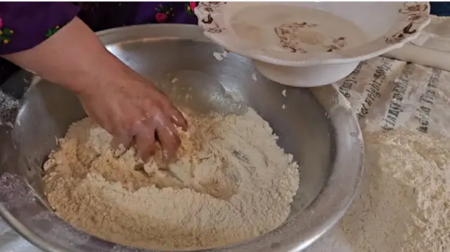 A woman's hand in flour as she prepares bread
