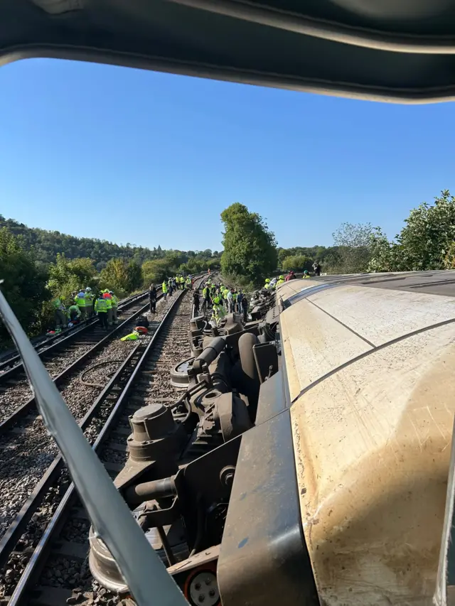 A train on its side off railway tracks.