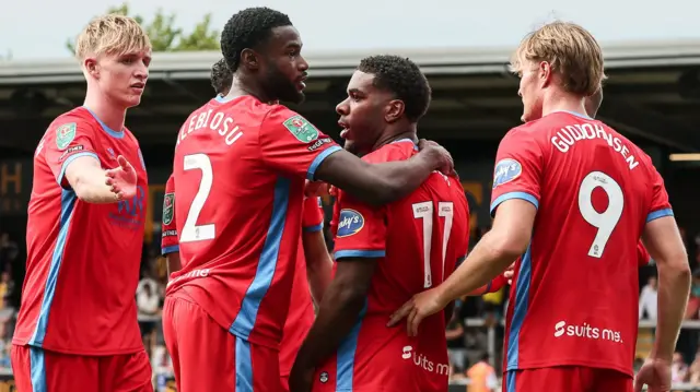 Blackburn Rovers players, wearing their red away kit, celebrate a goal against Burton Albion in the EFL Cup