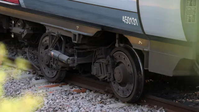 Two train wheels off the tracks and on the stony floor.