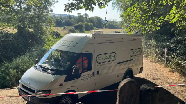 A white Rail Accident Investigation Branch van arrives in a field.