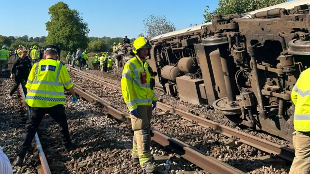 The train on its side with emergency services on the scene.