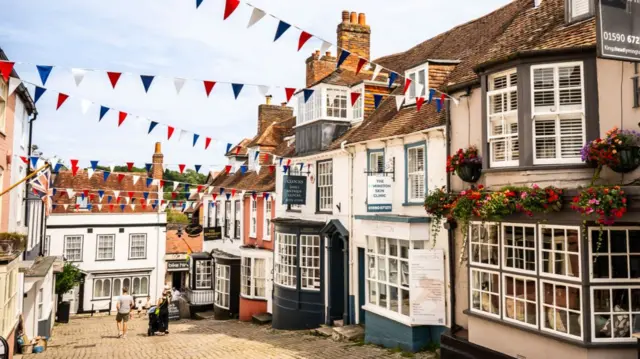 A cobbled sloping street lined by historic-style shop frontages