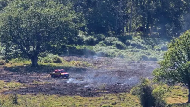 A fire service 4x4 in a smoking field.