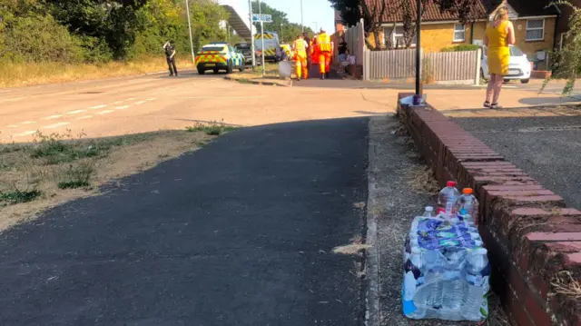 Bottles of water placed by the side of a residential road, where emergency crews are working