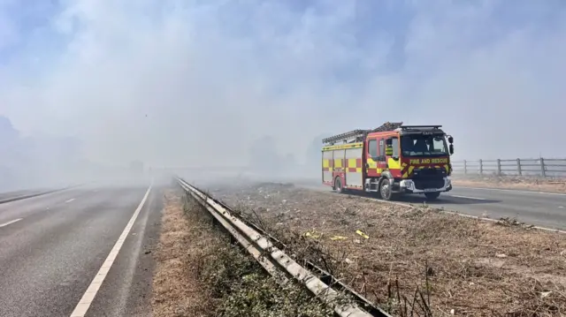 Fire engine surrounded by smoke on a dual carriageway.