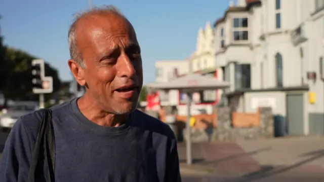 George Charalambous talks to the camera, wearing a blue t-shirt