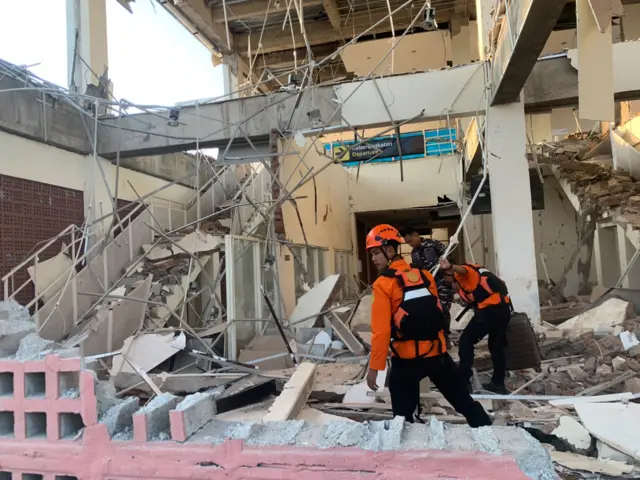 Rescuers inspect a heavily-damaged building following an earthquake, in Sikka, East Nusa Tenggara province, Indonesia, in August