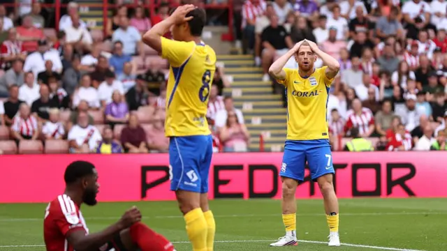 Birmingham players stand with their hands on their heads in the box