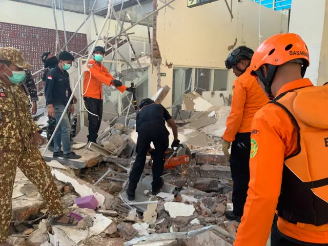 Rescuers inspect a heavily-damaged building following an earthquake, in Sikka, East Nusa Tenggara province, Indonesia, in August