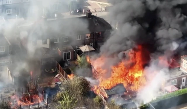 Smoke billowing from houses as flames engulf a garden.