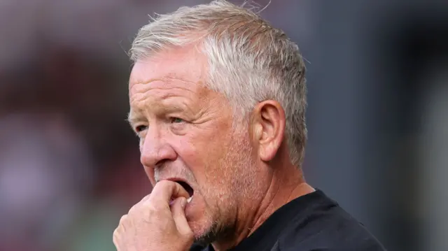 Chris Wilder stands on the touchline with his hand in his mouth
