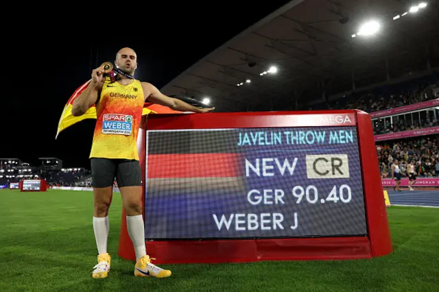 Gold medallist, Julian Weber of Team Germany, poses for a photo with the national flag beside the OMEGE display having set a new championship record of 90.40m