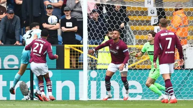 Max Kilman (far left) dives after heading the ball as three Burnley players watch it fly towards the net