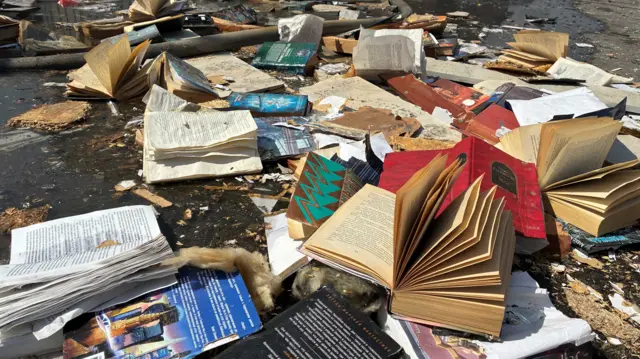 Books are seen on the floor surrounded by mud and debris