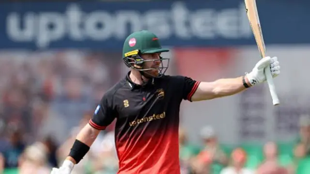 Nick Kelly raises his bat for his fifty