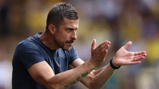 Alessio Dionisi holds his hands i front of him on the touchline