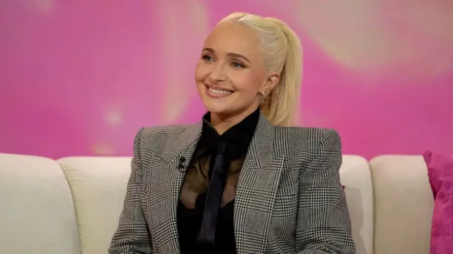 Hayden Panettiere sitting on a cream coloured sofa on a US show.