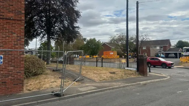The corner of a street with a metal fence surrounding one house