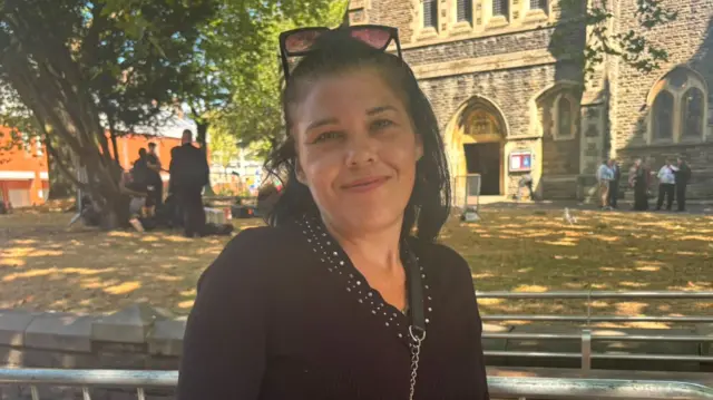 A woman smiles at the camera. It is a headshot and she is in front of a church