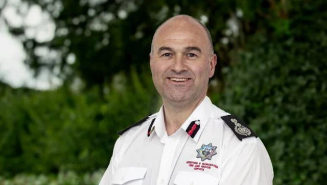 A man with a bald head and a white uniform shirt