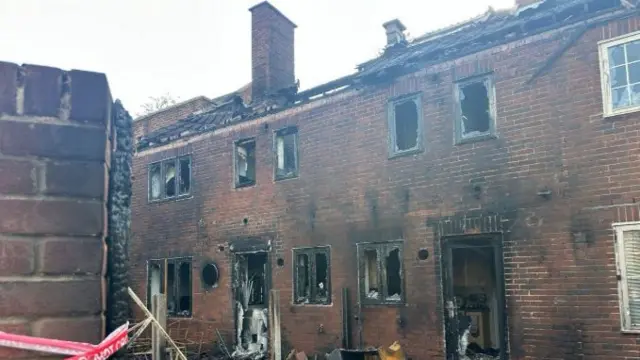 Two terraced homes severely burnt and damaged by a fire. The windows have been blown out, the doors are gone and part of the roof is missing.