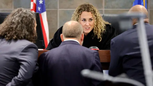 Judge leaning over her desk and speaking with attorneys