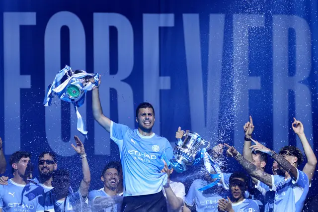 Rodri with the EFL Cup and FA Cup trophies