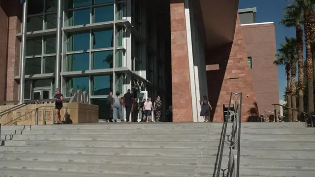 A handful of people walk into the courtroom