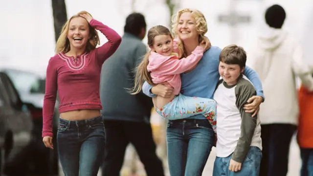 Panettiere on the left next to a woman who carries a small girl and has her arm around a young boy