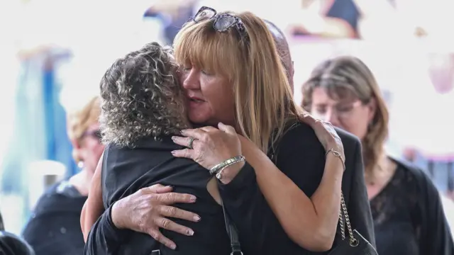 Guests attend the funeral of Bonnie Tyler dressed in black, hugging each other and looking emotional