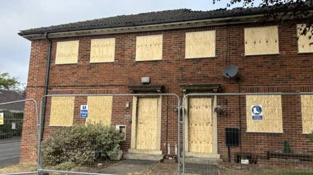 A boarded up building with metal fencing in front