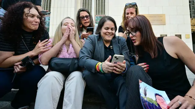 Laura Marquez-Garrett (C, gray blazer), plaintiffs' attorney for SMVLC (Social Media Victims Law Center), gathers with parents and family members of victims as they react to news that the jury has found Meta and YouTube liable in the social media addiction trial, outside the Los Angeles Superior Court , in Los Angeles, on March 25, 2026