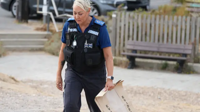 Police officer holding an evidence bag on the beach
