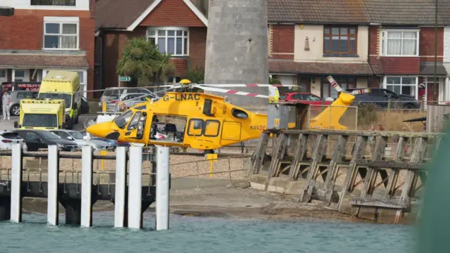 A yellow emergency services helicopter on a beach in Sussex.