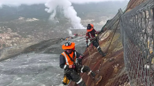 A man attached to a harness over a cliff ledge