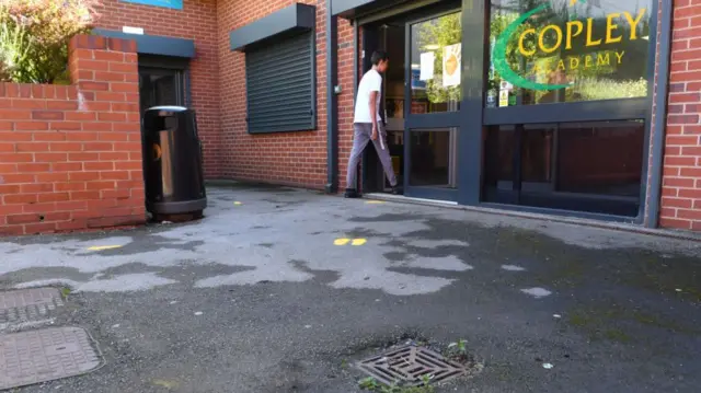 A young student walks into the entrance of the Copley Academy