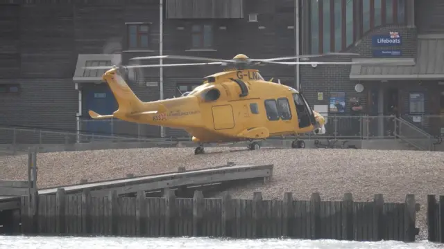 A yellow air ambulance on the stones of Shoreham beach