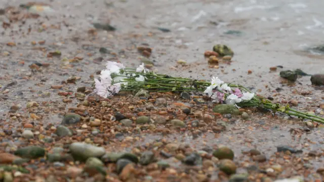 A bunch of flowers laying on the pebbles at the beach in Shoreham-by-Sea, Sussex.