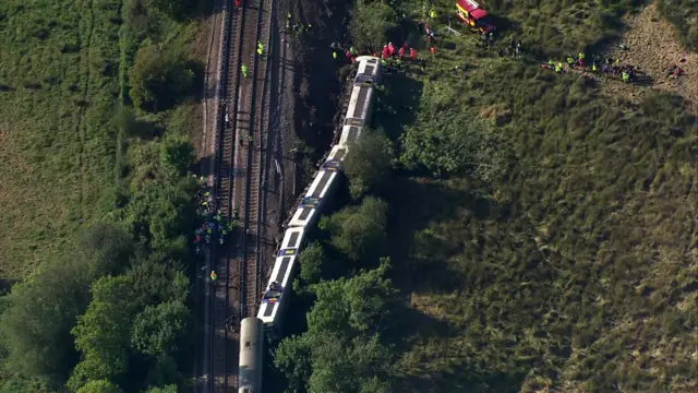 Image of three carriages of train falling off tracks from an aerial point of view
