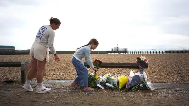 A mother and her young daughter lay flowers on the beach at Shoreham-by-Sea.