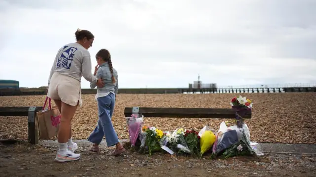 A mother and daughter lay flowers on the beach at Shoreham-by-Sea, West Sussex, near the RNLI station.