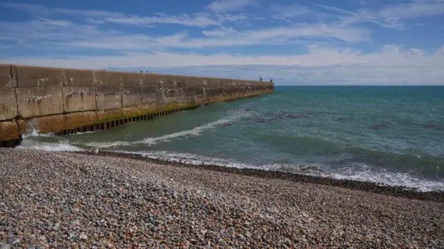 The beach, with pebbles and a sea wall.