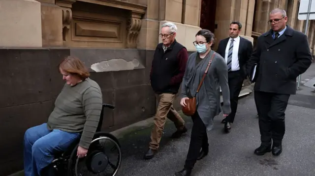Ian Wilkinson walking with four other people, with their heads down