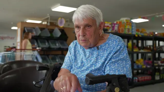 Rose pictured in the foodbank. She has short white hair and wears a blue t-shirt