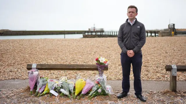 Tom Rutland, Labour MP for East Worthing and Shoreham stood next to flowers laid on the beach in Shoreham.
