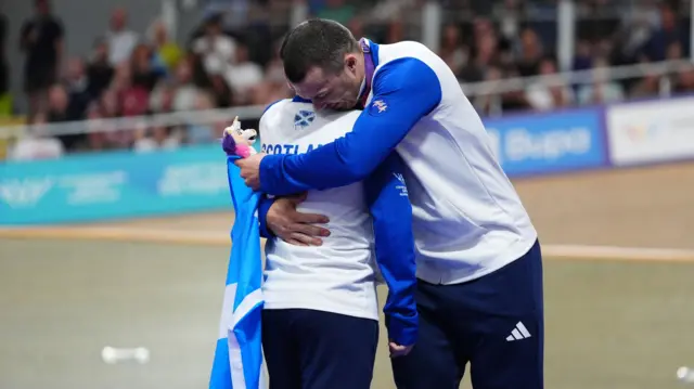 Neil Fachie embraces team-mate Aaron Pope after winning gold at the Commonwealth Games