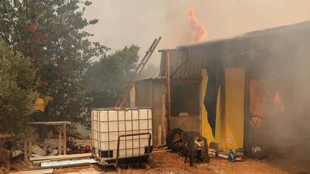 House burning in Greece, with flames and smoke visible